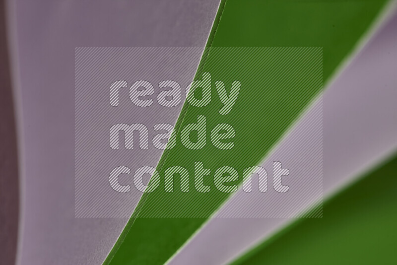 An abstract art showing purple and green paper sheets arranged in an overlapping curves