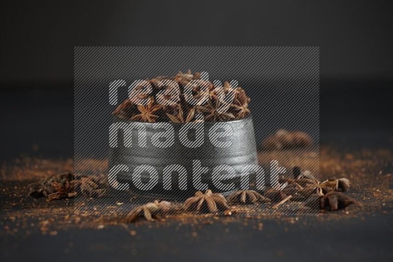 Star Anise in a black bowl with sprinkled anise on black flooring