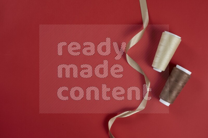 مجموعة من أدوات الخياطة والتفصيل بنية وحمراء اللون على خلفية حمراء