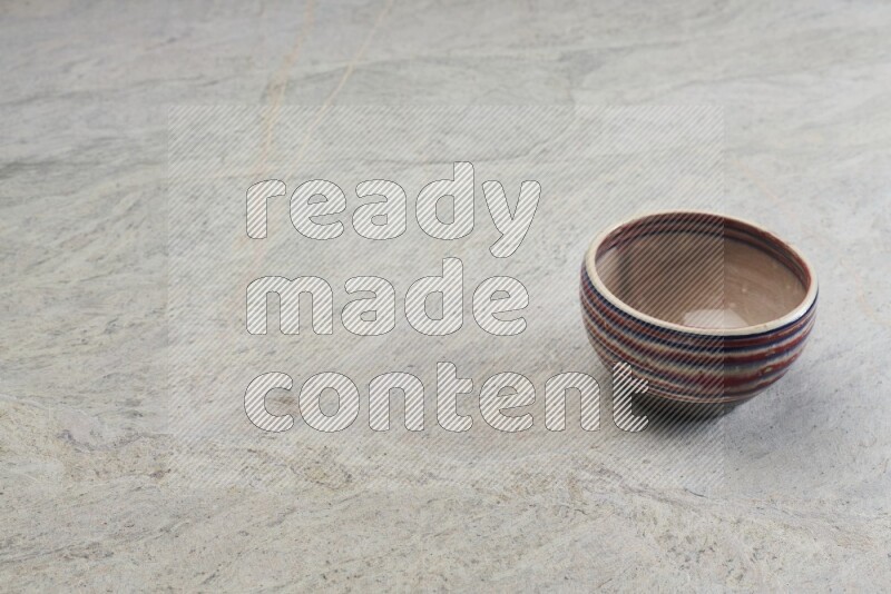 A multicolored pottery bowl on grey marble background