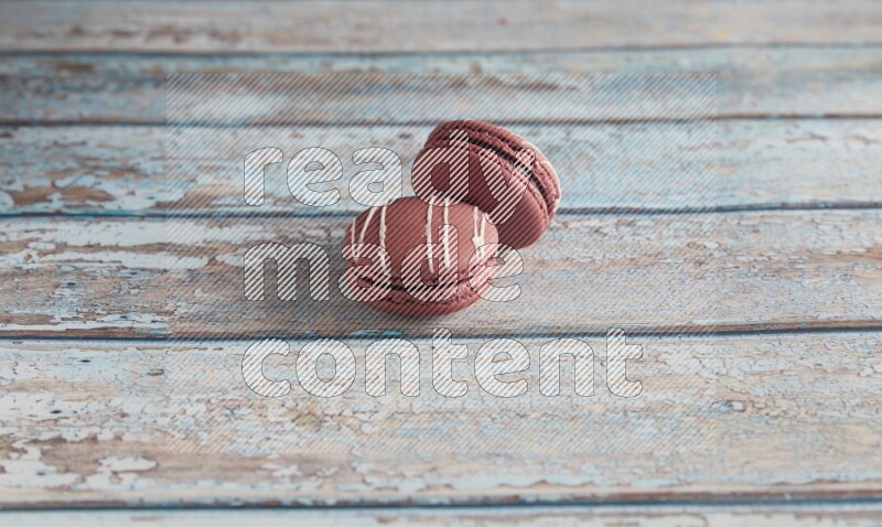 45º Shot of two Red Poppy Flower macarons on light blue wooden background