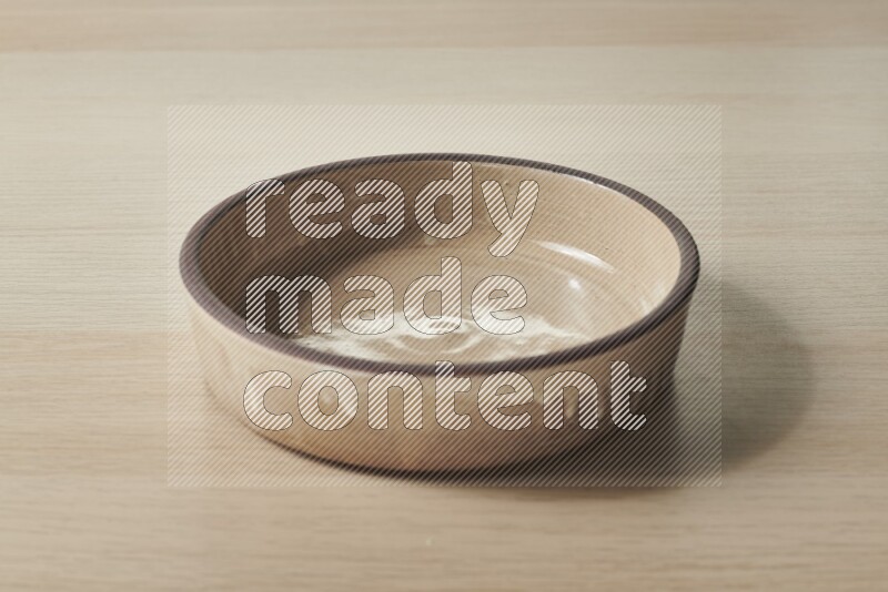 A beige pottery oven plate on light wooden background