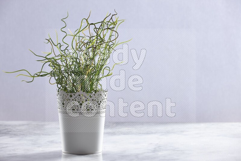Green artificial plant in white decorative pot on grey marble background