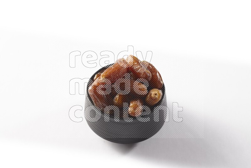 Dates in a black pottery bowl on white background