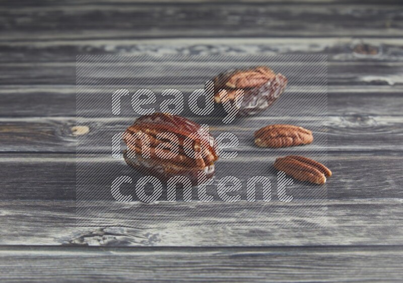 two pecan stuffed madjoul date on a wooden grey background