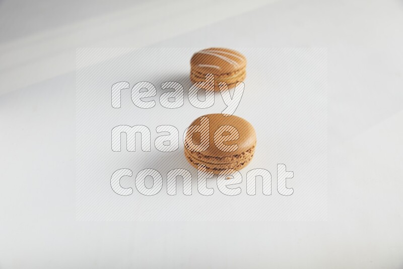 45º Shot of of two assorted Brown Irish Cream, and Brown Maple Taffy macarons  on white background