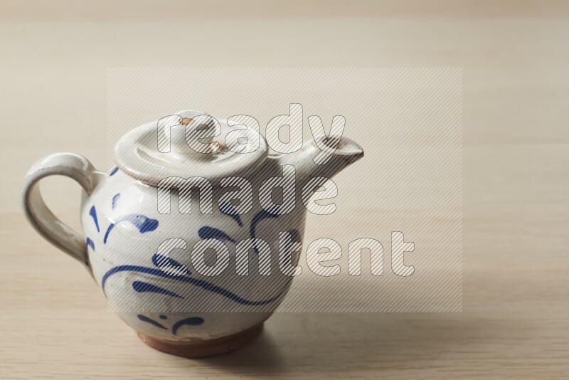 A pottery teapot on light wooden background
