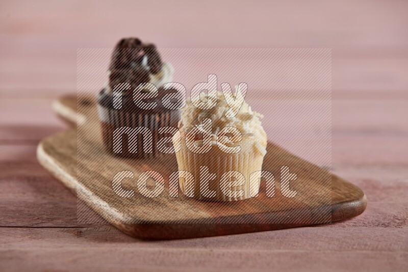 Vanilla mini cupcake topped with coconut on a wooden board