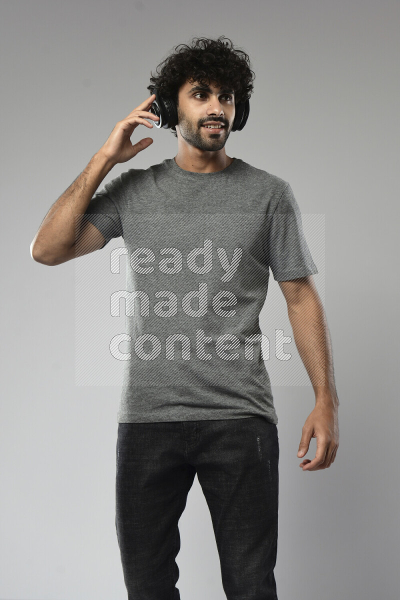 A man wearing casual standing and putting on headphones on white background