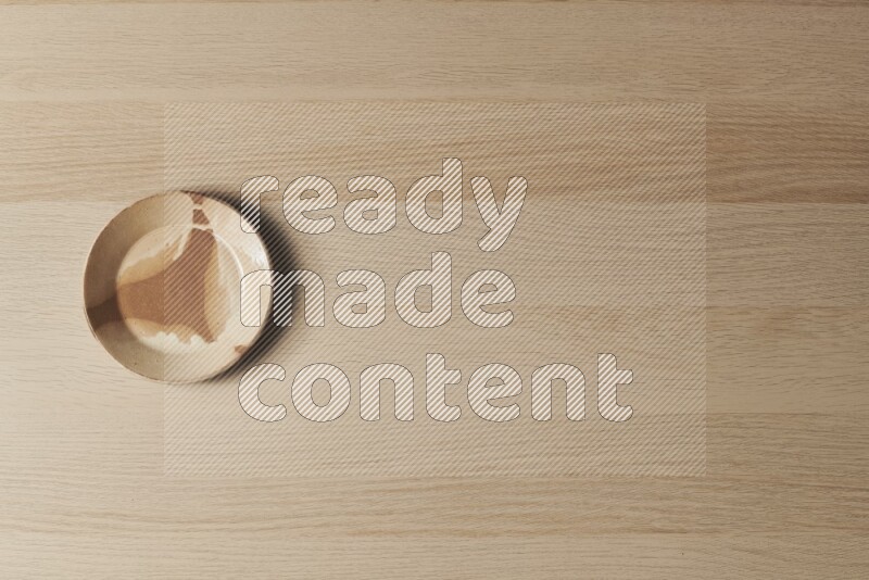 A multicolored pottery plate on light wooden background