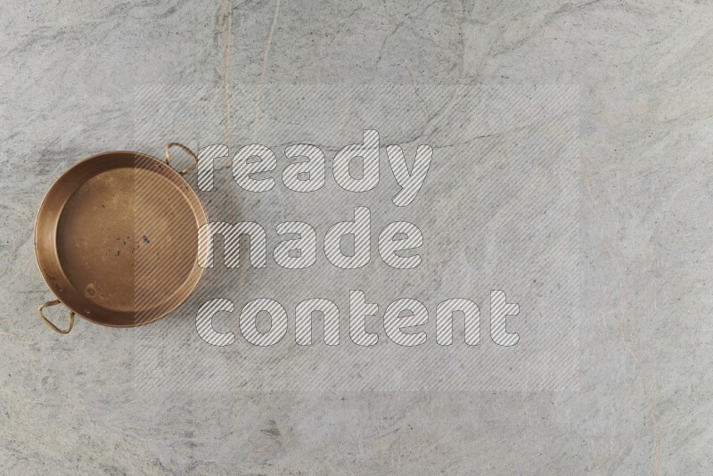 A small copper pan on grey marble background