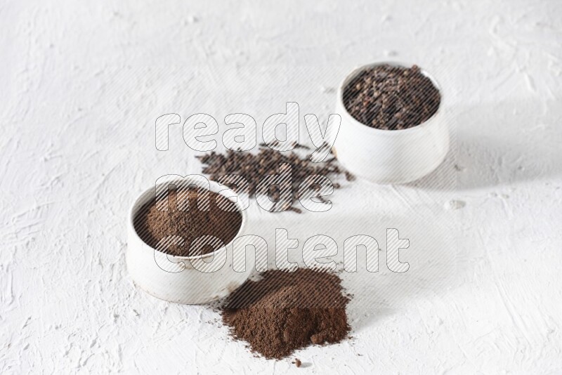 وعاءين من السيراميك بيج اللون، أحدهما مملوء بالقرنفل والآخر مملوء بالبودرة على أرضية بيضاء