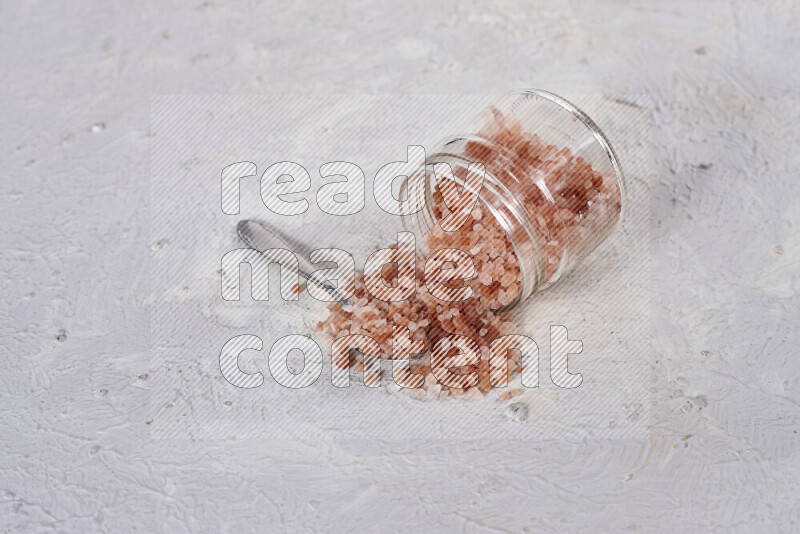 A glass jar full of coarse himalayan salt crystals on white background