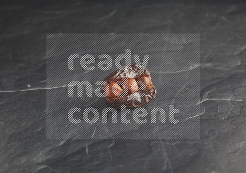 hazelnuts stuffed madjoul date on a black textured background