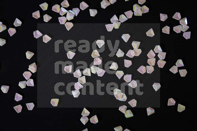 Colorful plastic shards for decoration scattered on a black background