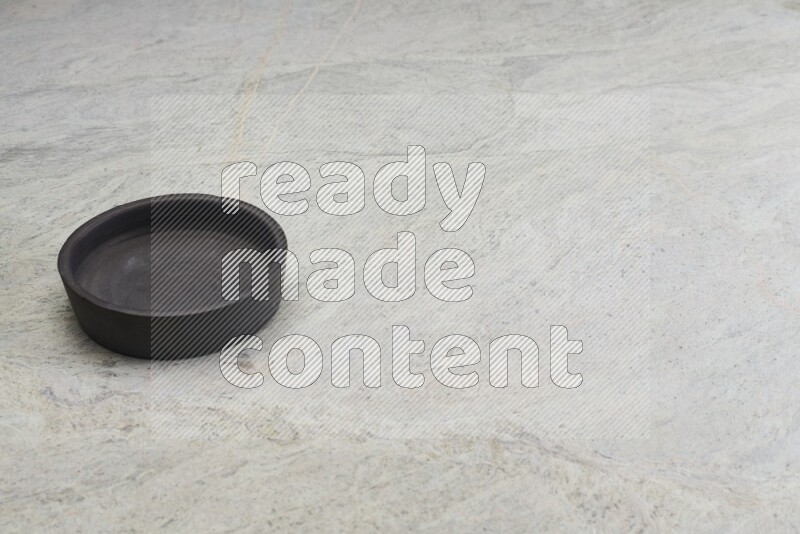 A black pottery oven bowl on grey marble background