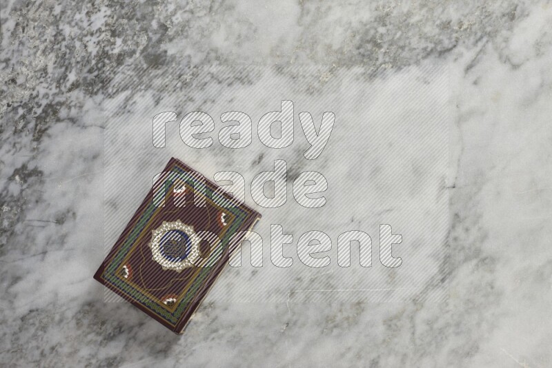 Quran with a prayer beads on grey marble background