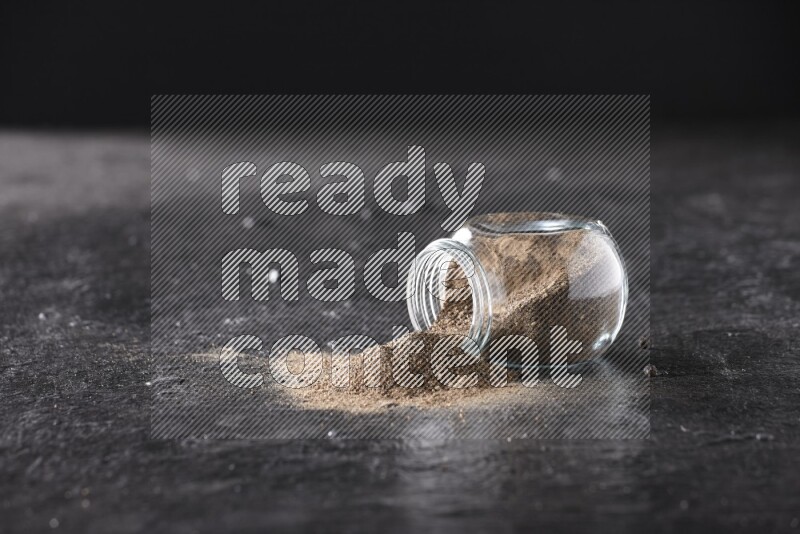 بودرة الفلفل الأسود في وعاء زجاجي مقلوب علي خلفية سوداء