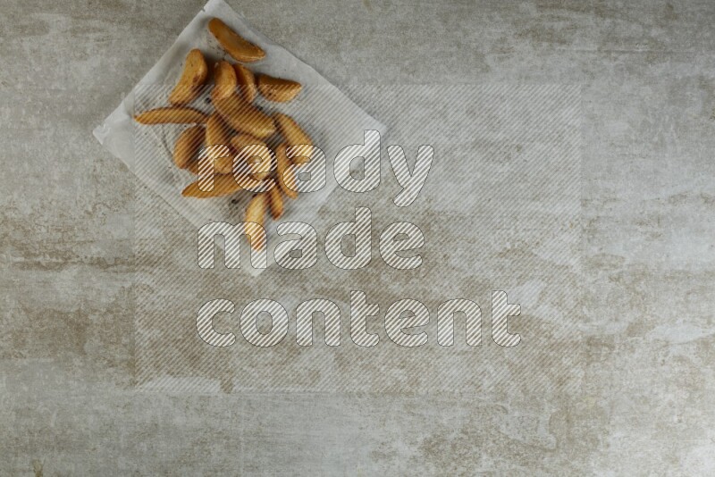 wedges potato on parchment paper on grey textured counter top