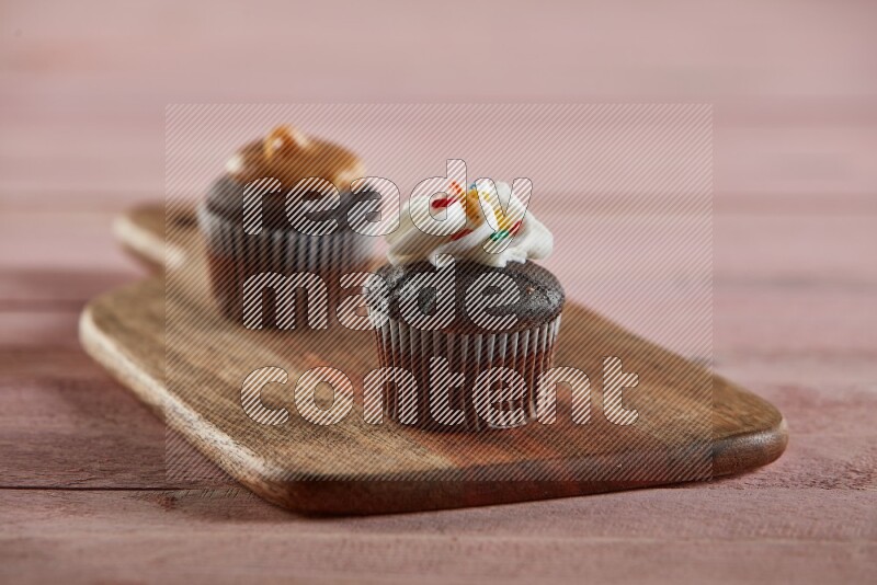 Chocolate mini cupcake topped with cream on a wooden board