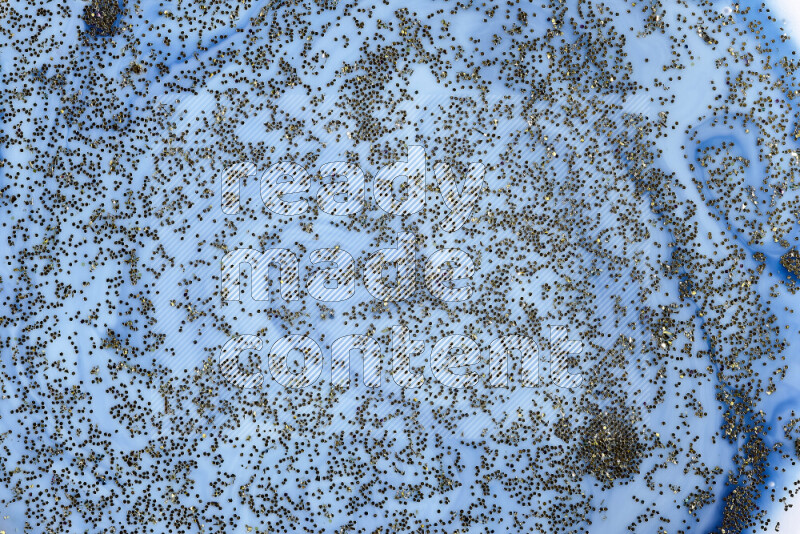 لقطة مقربة لبريق ذهبي متلألئ منتشر على خلفية من اللون الأزرق في حركات دائرية