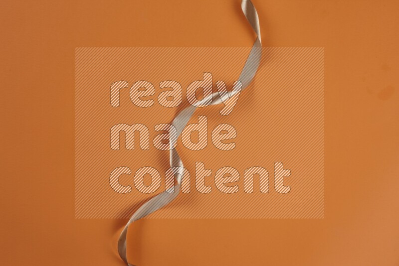 A brown collection of sewing and tailoring tools arranged on a orange background