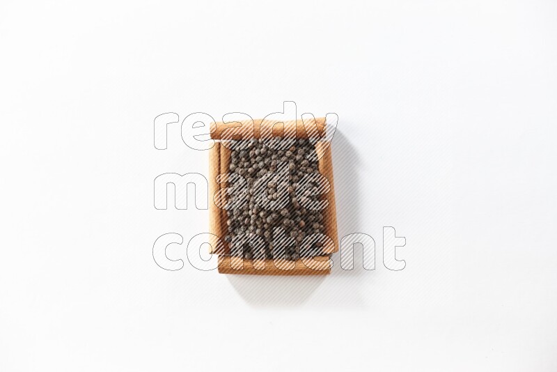 A single square of cinnamon sticks full of black pepper on white flooring