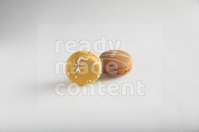 45º Shot of of two assorted Brown Irish Cream, and Yellow Piña Colada macarons on white background