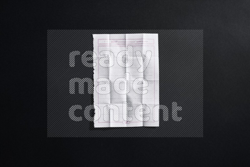 Folded notebook sheet on black background