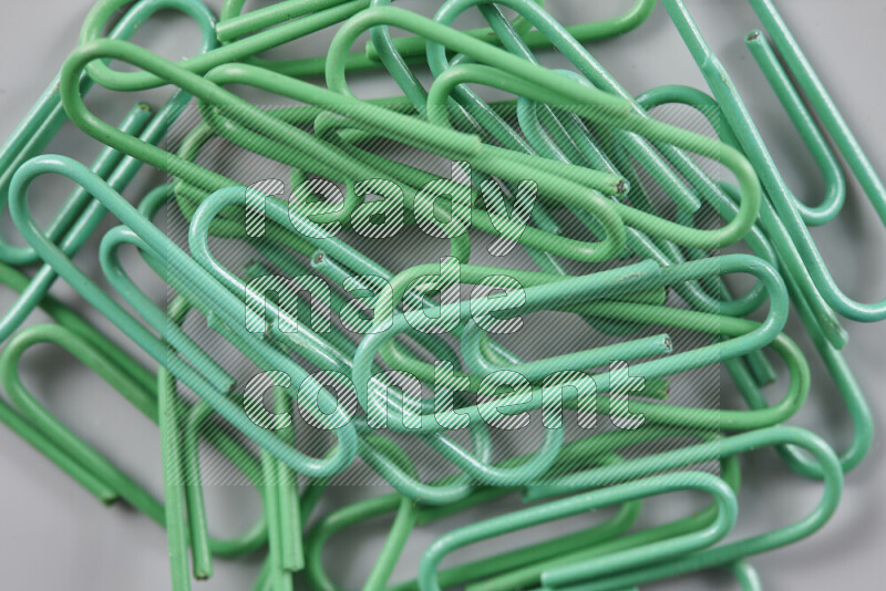 Green paper clips isolated on a grey background