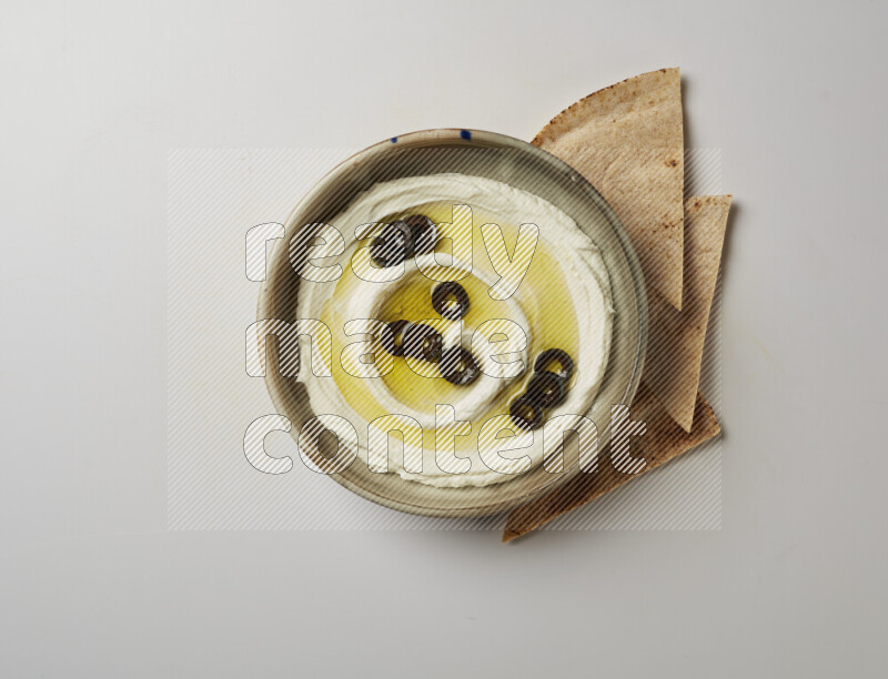 Lebnah garnished with sliced olives in a grey pottery plate on a white background
