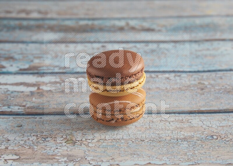 45º Shot of of two assorted Brown Irish Cream, and Yellow, and Brown Chai Latte macarons  on light blue background