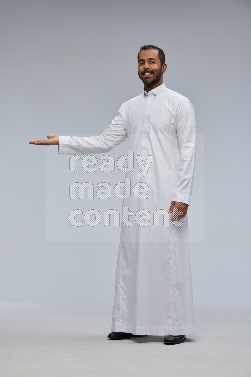 Saudi man Wearing Thob standing interacting with the camera on Gray background