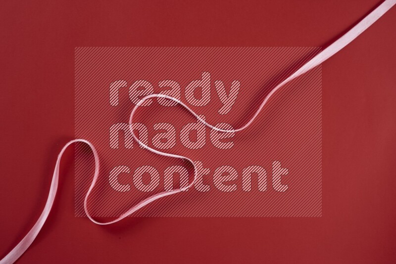 A pink and red collection of sewing and tailoring tools arranged on a red background