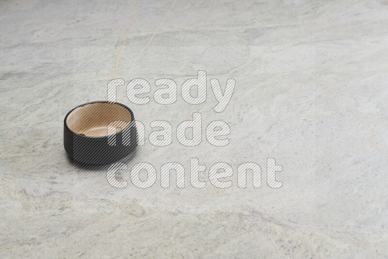A black pottery bowl on grey marble background