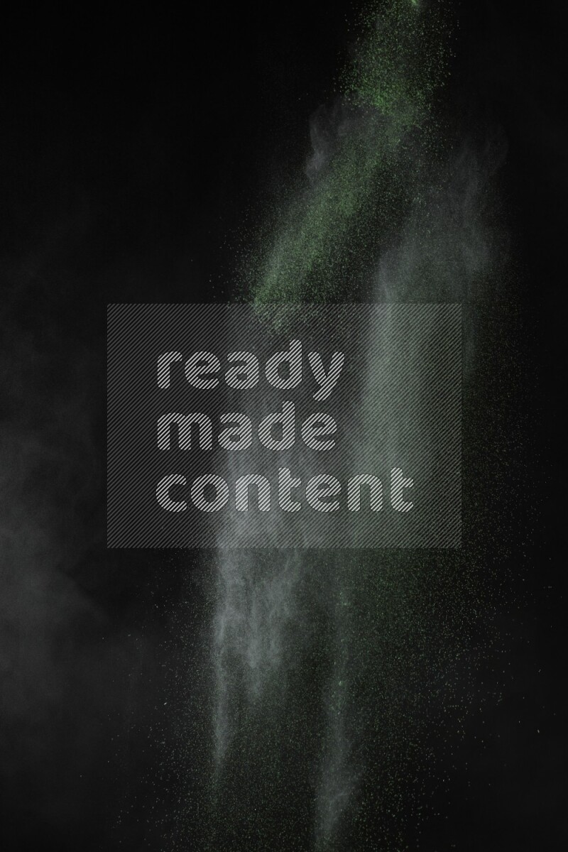 A side view of green powder explosion on black background