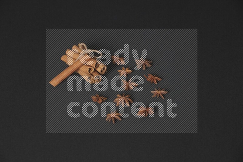 Cinnamon sticks stacked and bounded and star anise on black background