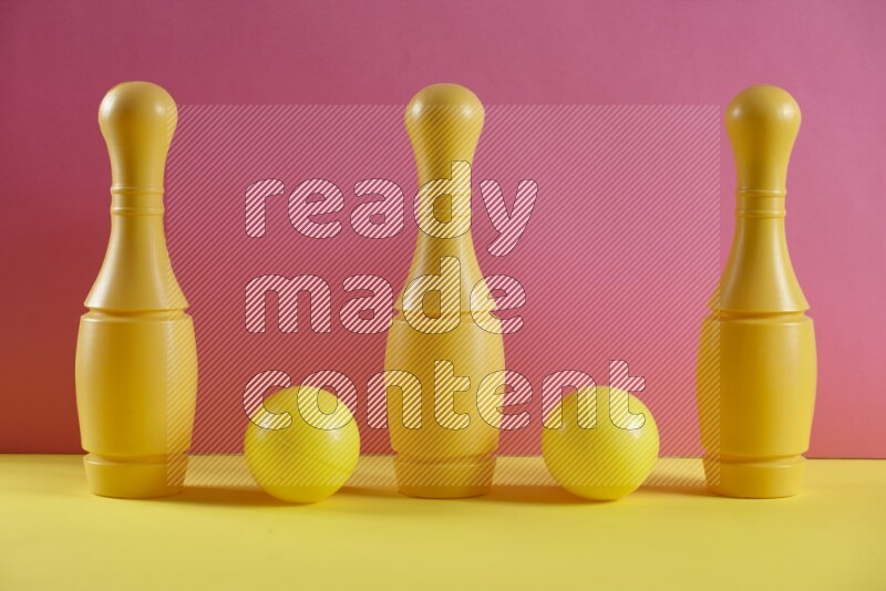 Plastic bowling pins with balls on pink and yellow background (kids toys)
