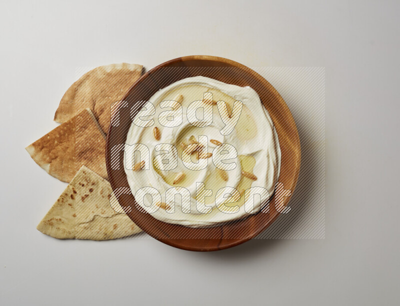 Lebnah garnished with pine nuts in a wooden plate on a white background