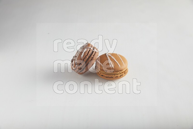 45º Shot of of two assorted Brown Irish Cream, and Brown white Chocolate Caramel macarons on white background