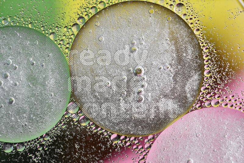 Close-ups of abstract oil bubbles on water surface in shades of yellow, green and pink