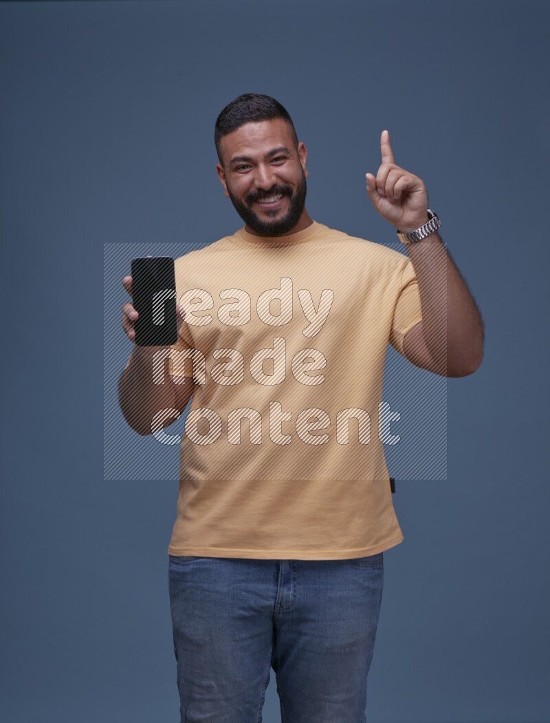 A man Showing His Smart Phone on Blue Background wearing Orange T-shirt