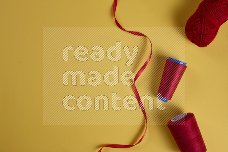 مجموعة من أدوات الخياطة والتفصيل حمراء اللون على خلفية صفراء