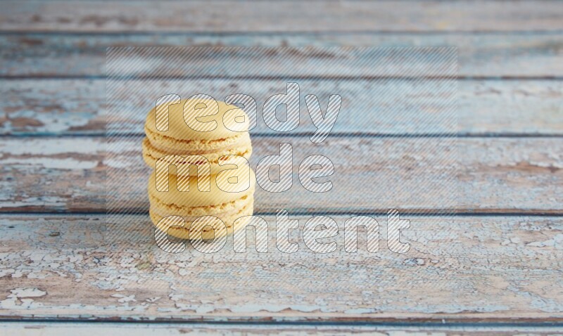 45º Shot of two Yellow Vanilla macarons on a light blue wooden background