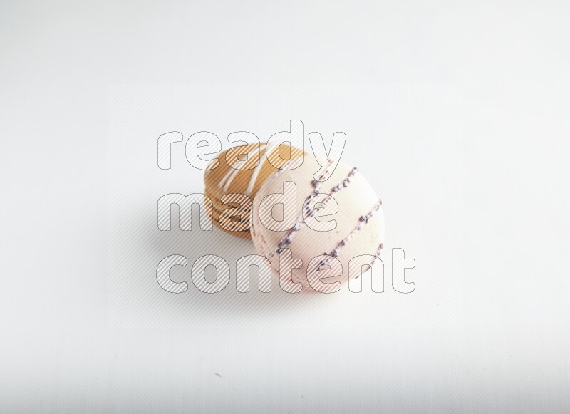 45º Shot of of two assorted Brown Irish Cream, and pink orange blossom macarons on white background