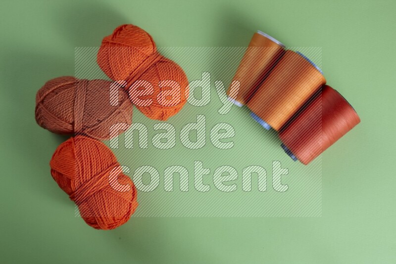 مجموعة من أدوات الخياطة والتفصيل برتقالية اللون على خلفية خضراء