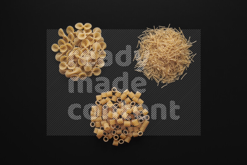 Different pasta types in bunches on black background