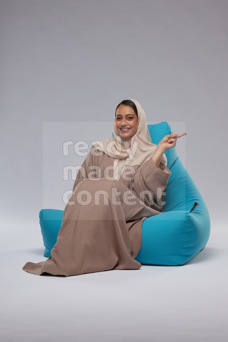 A woman sitting on a blue beanbag and interacting with the camera