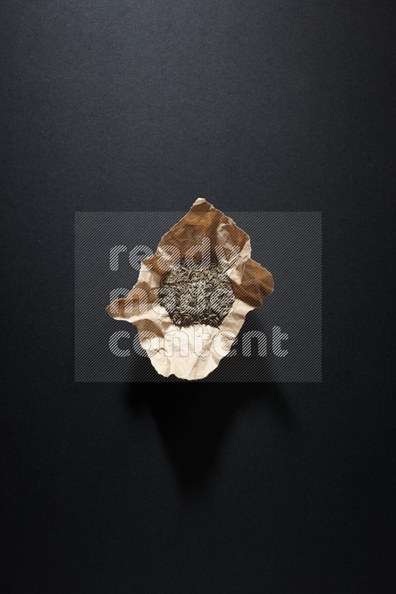 حبوب الكمون في قطعة من الورق على خلفية سوداء