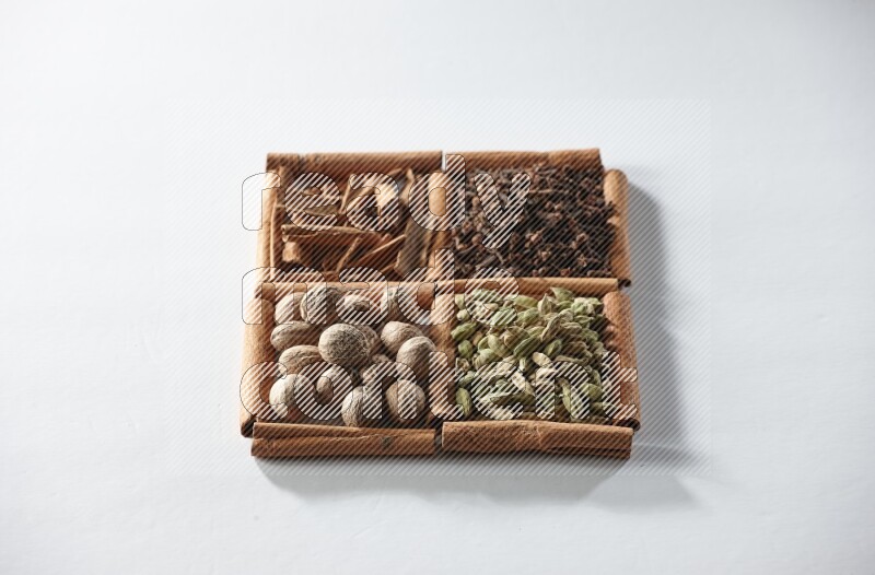 4 squares of cinnamon sticks full of cardamom, cinnamon, cloves and nutmeg on white flooring